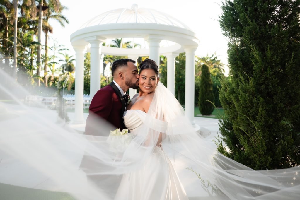 Maria and Fabio sharing a wedding portrait beside the white gazebo at Gran Paraiso Gardens