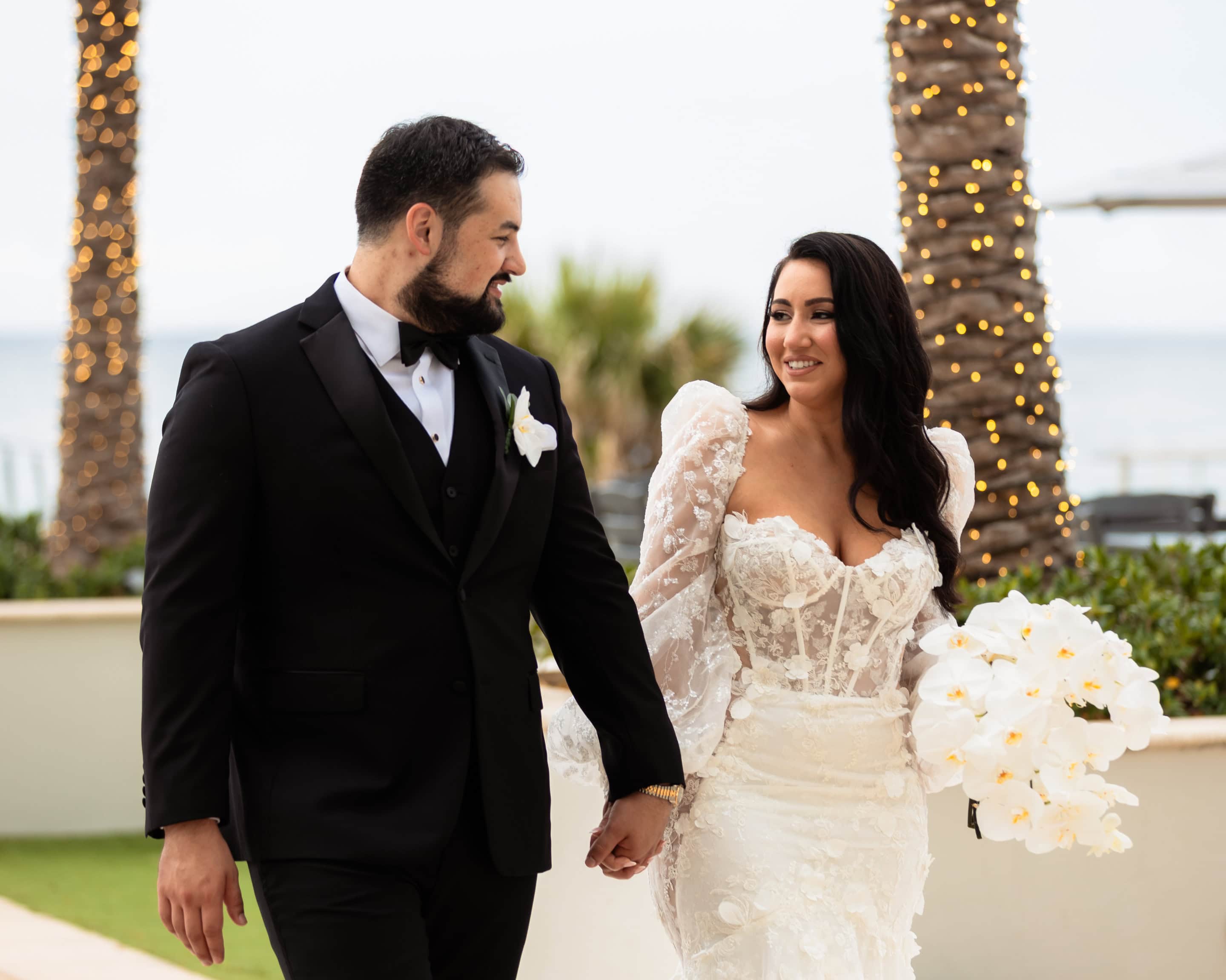 Arlene and René walking hand in hand beside the palms at Marriott Harbor Beach