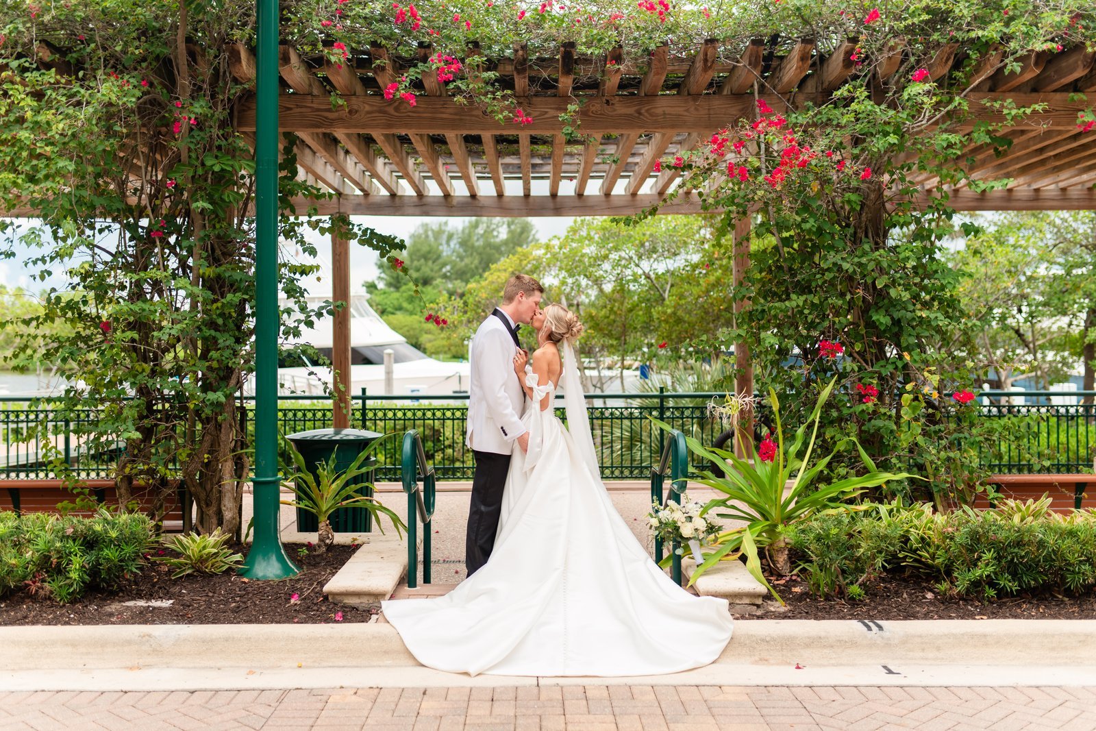 Reese and Jacob beneath a flowering pergola at Harbourside Place on their Wyndham Grand Jupiter wedding day